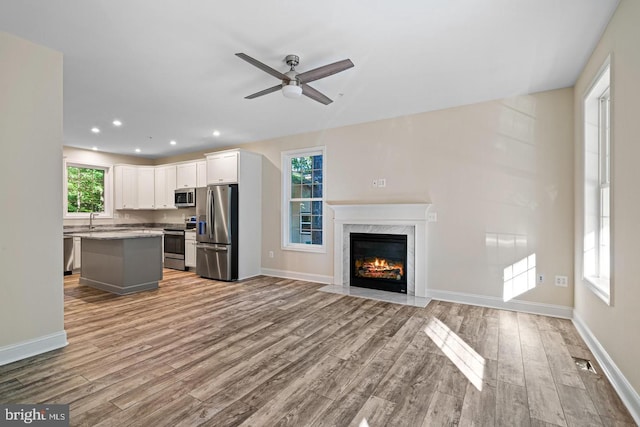 unfurnished living room with a high end fireplace, light hardwood / wood-style flooring, and a healthy amount of sunlight