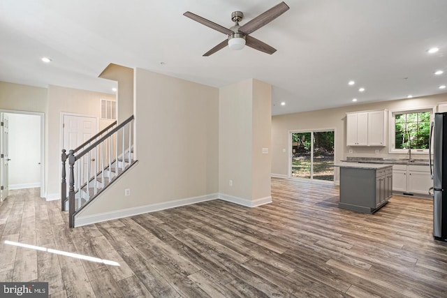 kitchen with stainless steel fridge, light wood-type flooring, gray cabinetry, white cabinets, and a kitchen island