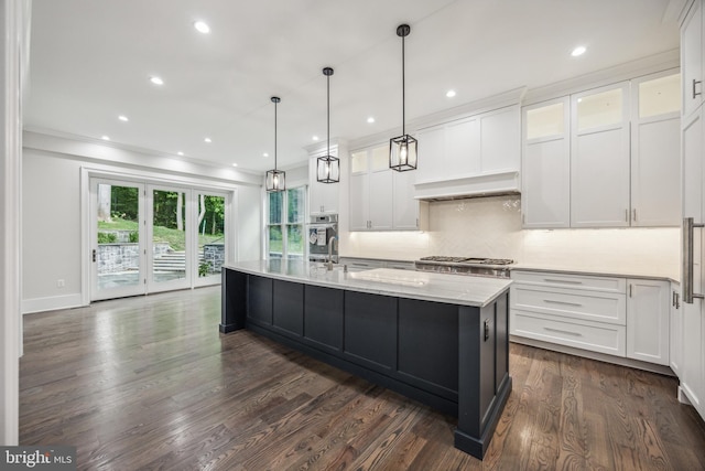 kitchen with hanging light fixtures, dark hardwood / wood-style floors, white cabinetry, and a kitchen island with sink