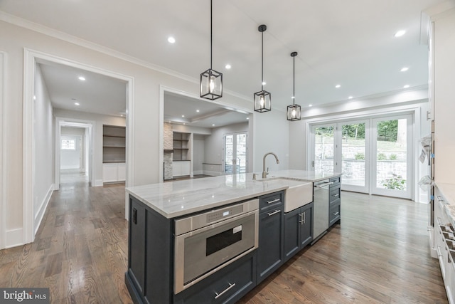 kitchen with light stone countertops, sink, stainless steel dishwasher, an island with sink, and decorative light fixtures