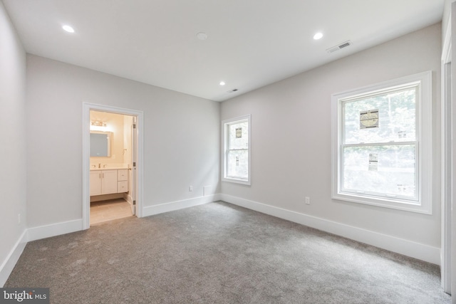 unfurnished bedroom featuring ensuite bath and light carpet