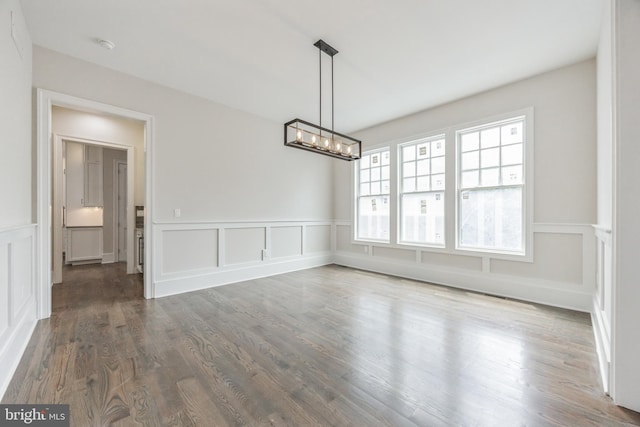 unfurnished dining area with a notable chandelier and dark hardwood / wood-style flooring