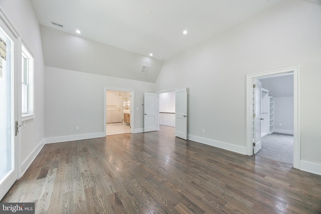 unfurnished bedroom featuring connected bathroom, high vaulted ceiling, and dark hardwood / wood-style floors