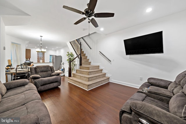 living room featuring dark wood-type flooring and ceiling fan with notable chandelier