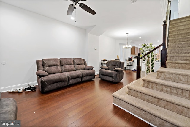 living room featuring ceiling fan with notable chandelier and dark wood-type flooring