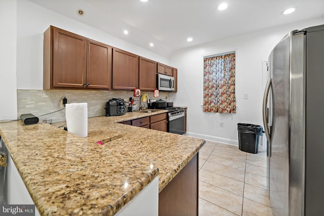 kitchen with light stone countertops, kitchen peninsula, and stainless steel appliances