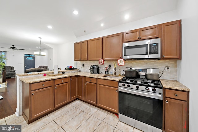 kitchen with kitchen peninsula, ceiling fan, stainless steel appliances, backsplash, and sink