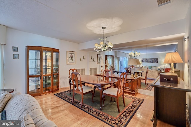 dining area featuring a wealth of natural light, light wood-type flooring, and a notable chandelier