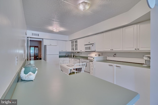 kitchen with white cabinetry, white appliances, and a textured ceiling