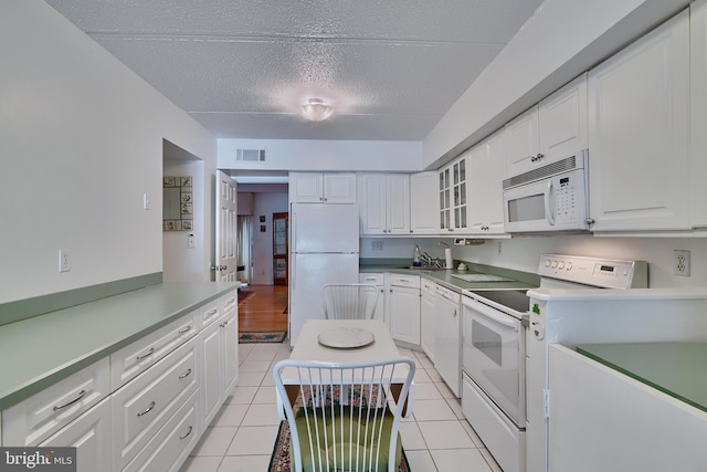 kitchen with white appliances, white cabinets, sink, light tile patterned floors, and a textured ceiling