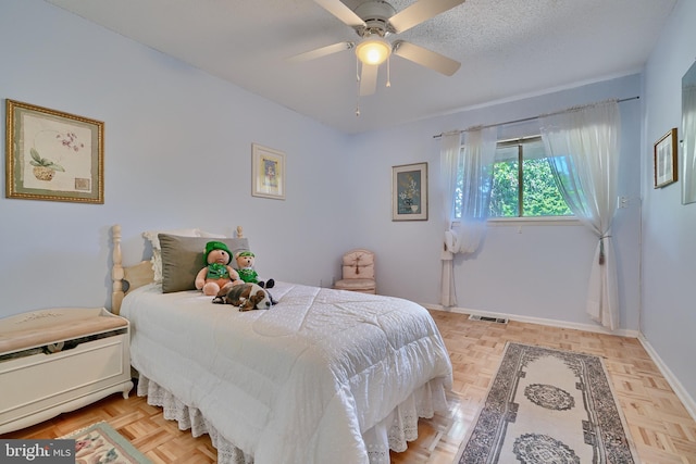 bedroom with light parquet floors, a textured ceiling, and ceiling fan