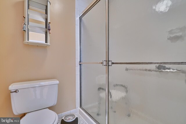 bathroom featuring a shower with shower door and toilet