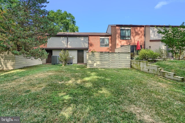 back of property with central AC and a lawn