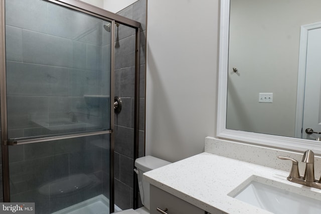 bathroom featuring vanity, a shower with door, and toilet