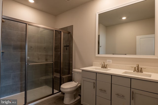 bathroom with toilet, double sink vanity, an enclosed shower, and tile patterned flooring