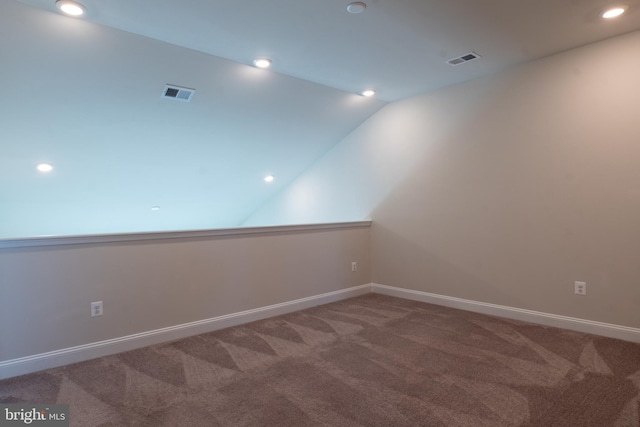 spare room featuring carpet floors and vaulted ceiling