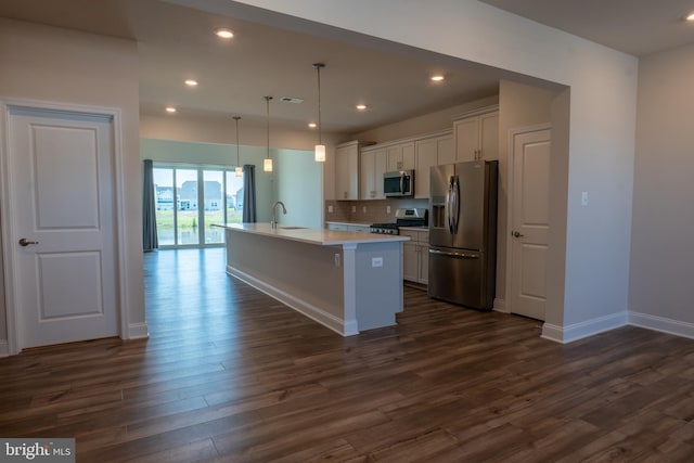 kitchen featuring dark hardwood / wood-style flooring, an island with sink, stainless steel appliances, decorative backsplash, and decorative light fixtures