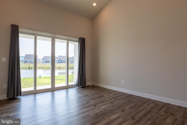 empty room with wood-type flooring, a water view, and high vaulted ceiling