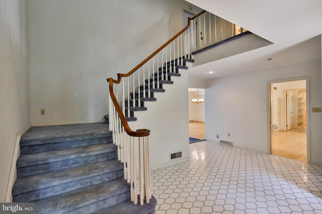 stairs featuring a chandelier