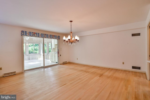 unfurnished room with a notable chandelier and light hardwood / wood-style floors