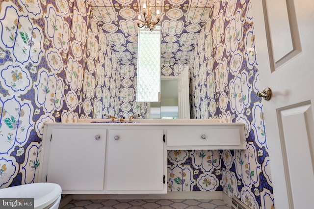 bathroom featuring vanity, toilet, and an inviting chandelier