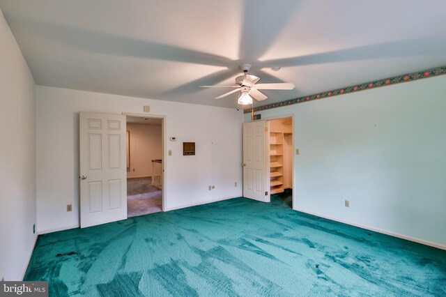 unfurnished bedroom featuring carpet, ceiling fan, a spacious closet, and a closet