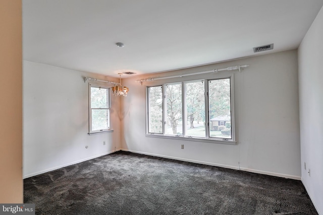 carpeted spare room with an inviting chandelier