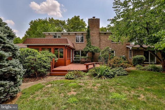 rear view of house with a deck and a lawn