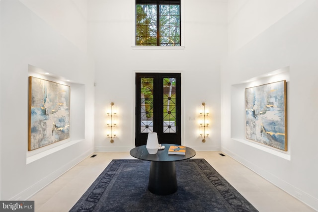 foyer entrance featuring light tile patterned floors, french doors, and a towering ceiling