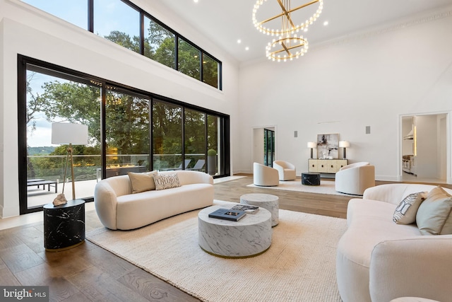 living room with a towering ceiling, an inviting chandelier, and hardwood / wood-style floors