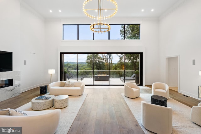 living room featuring a fireplace, a healthy amount of sunlight, a towering ceiling, and an inviting chandelier