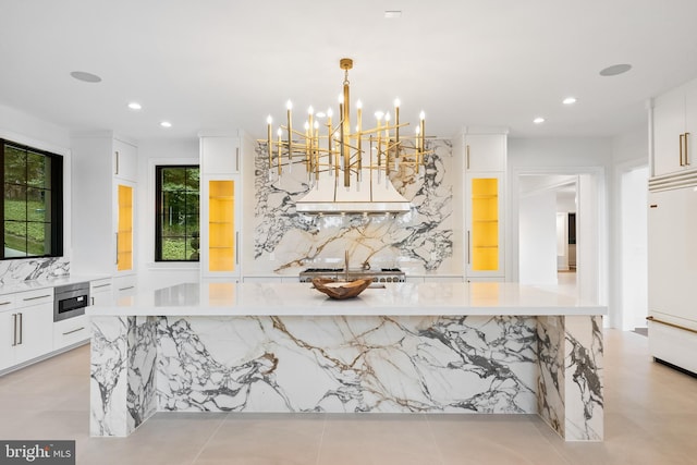 kitchen featuring a wealth of natural light, decorative light fixtures, white cabinetry, built in appliances, and decorative backsplash