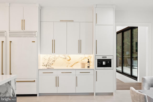 bar with light tile patterned floors, white cabinetry, paneled refrigerator, and tasteful backsplash