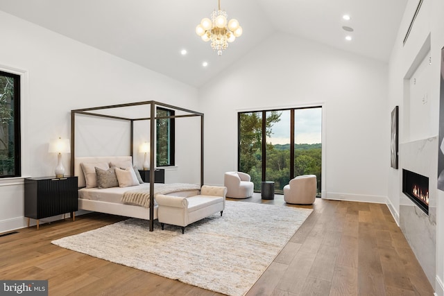 bedroom featuring a chandelier, light hardwood / wood-style flooring, and high vaulted ceiling