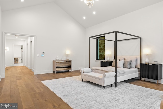 bedroom with high vaulted ceiling, a chandelier, and hardwood / wood-style flooring