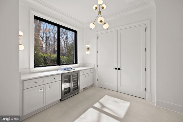 kitchen with white cabinets, wine cooler, hanging light fixtures, light tile patterned floors, and crown molding