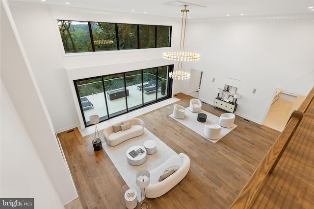 living room featuring a towering ceiling, hardwood / wood-style flooring, and a notable chandelier