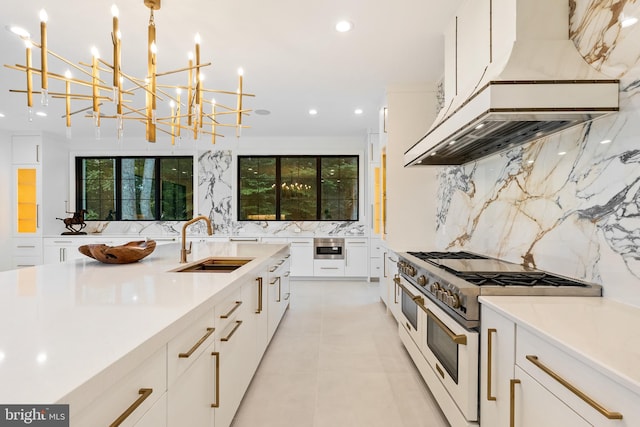 kitchen with double oven range, decorative backsplash, pendant lighting, white cabinets, and sink