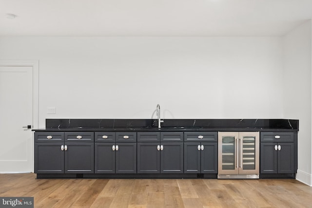 interior space featuring sink, beverage cooler, and light hardwood / wood-style flooring