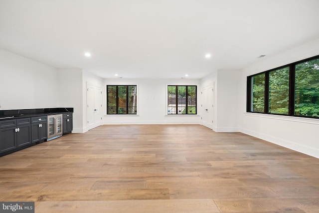 unfurnished living room with light hardwood / wood-style floors and wine cooler