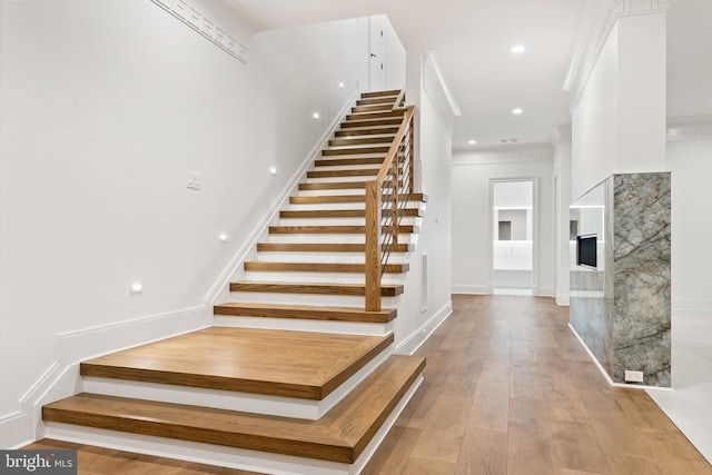 staircase with ornamental molding and wood-type flooring