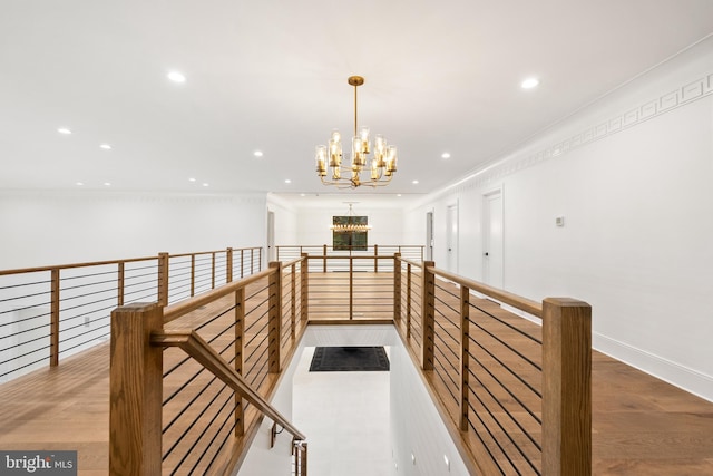 hallway with hardwood / wood-style floors, crown molding, and a chandelier