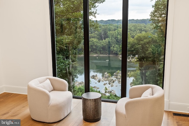 sitting room featuring plenty of natural light, a water view, and wood-type flooring