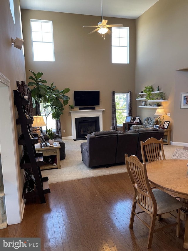 living room featuring ceiling fan, hardwood / wood-style floors, and a high ceiling