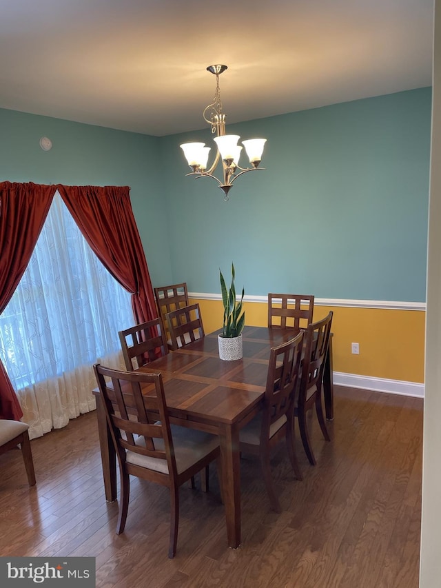 dining space featuring dark wood-type flooring and a chandelier