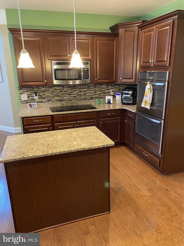 kitchen featuring decorative light fixtures, light wood-type flooring, and stainless steel appliances