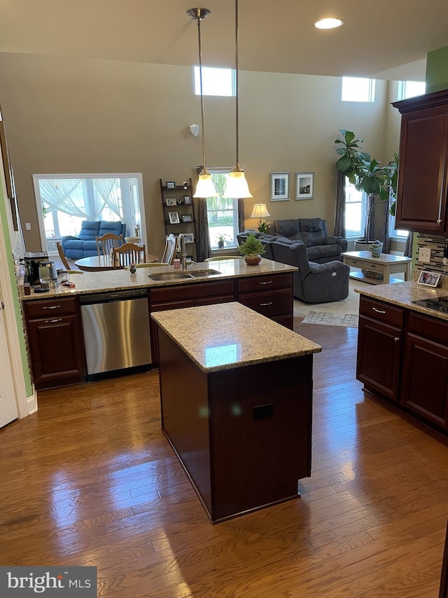 kitchen with a center island, sink, dark wood-type flooring, stainless steel dishwasher, and dark brown cabinets