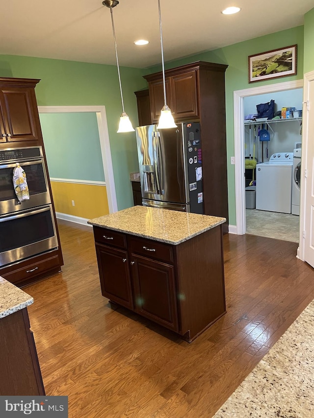 kitchen with light stone counters, dark brown cabinets, stainless steel appliances, independent washer and dryer, and hanging light fixtures