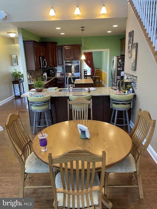 kitchen with kitchen peninsula, tasteful backsplash, stainless steel appliances, sink, and pendant lighting