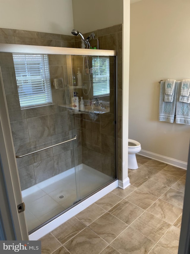 bathroom with tile patterned flooring, toilet, and a shower with door